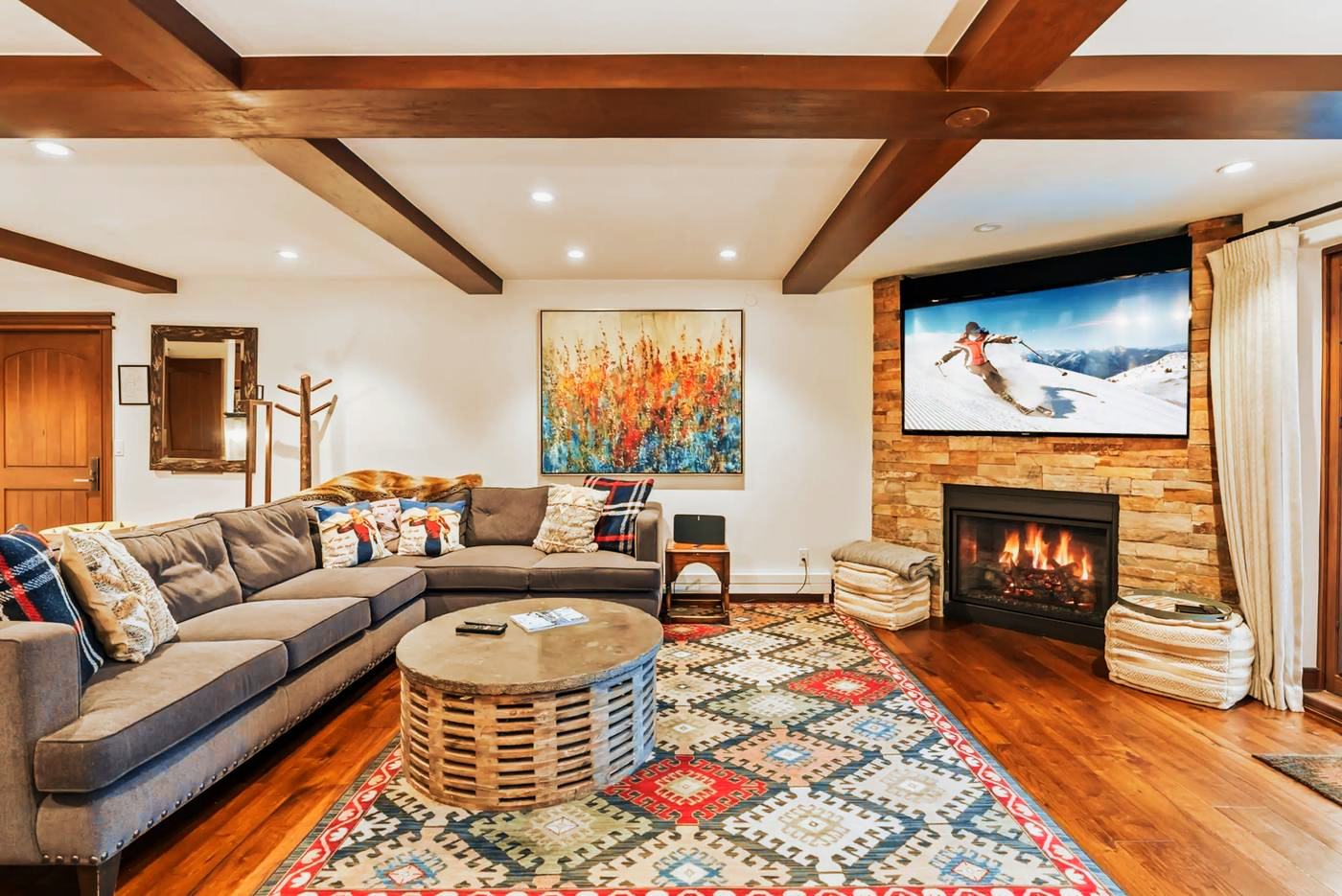 The great room at 291 Bridge Street, fire lit, under a beamed ceiling